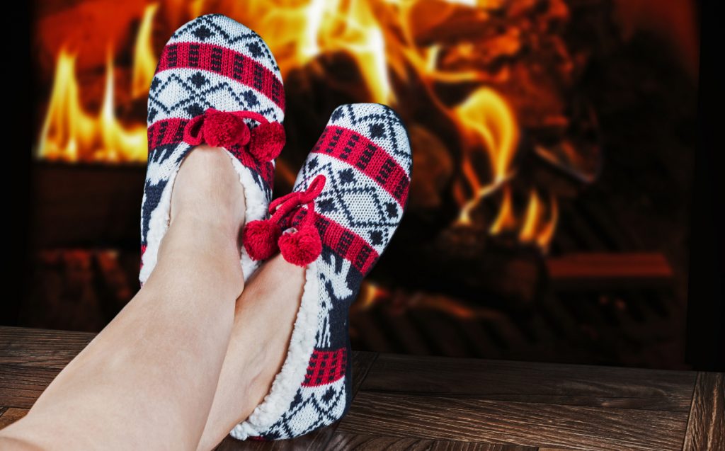 Christmas female slippers on the background of a burning fireplace