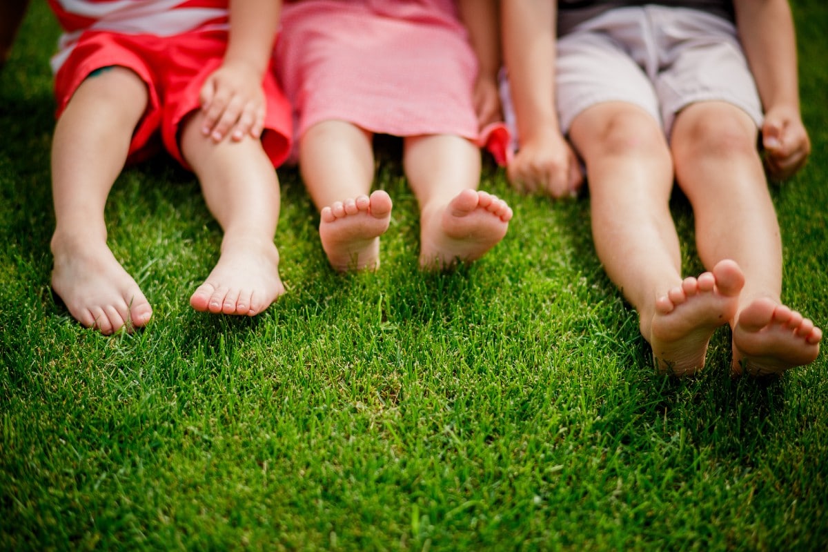 closeup of 3 children's feet sitting in the grass