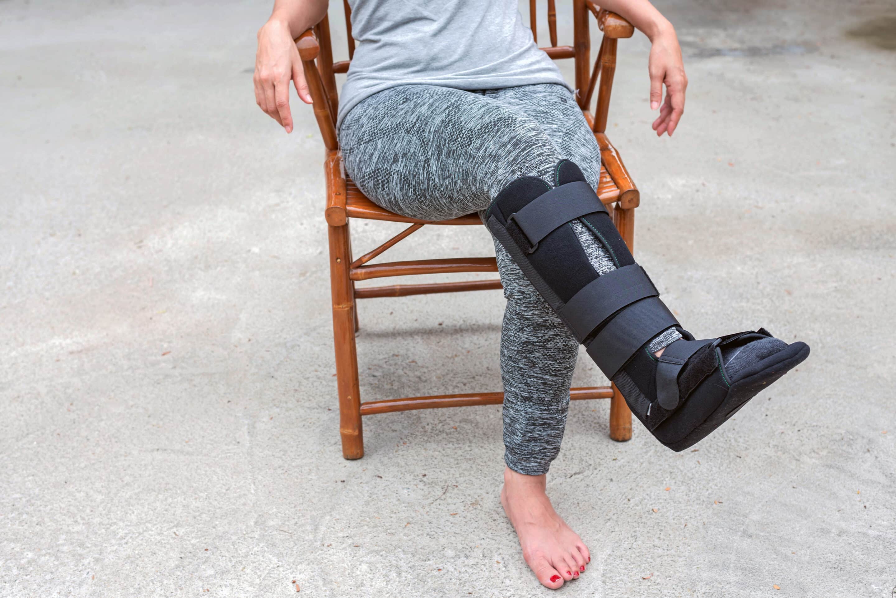 injury woman with black cast on leg sitting on wooden chair at home, Travel insurance concept injury woman with black cast on leg sitting on wooden chair at home, Travel insurance concept