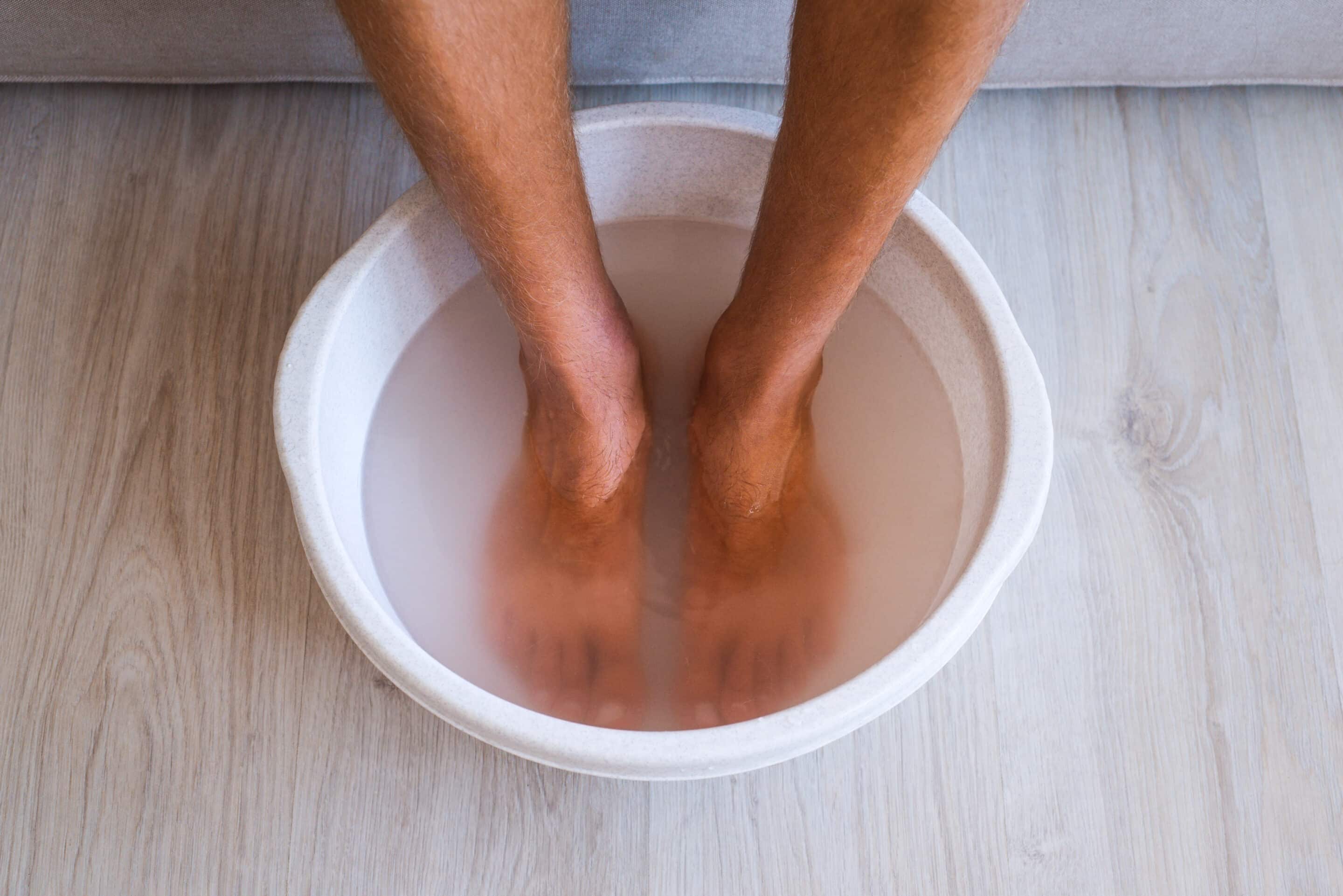 man soaking his feet in warm water tub. 